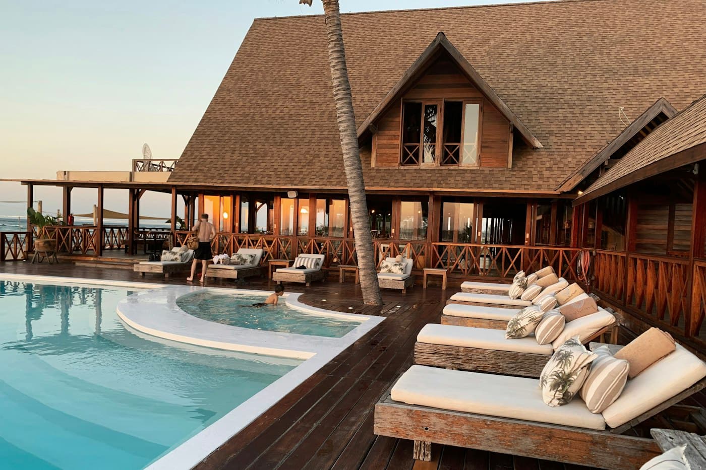 A resort pool deck with sun loungers at golden hour